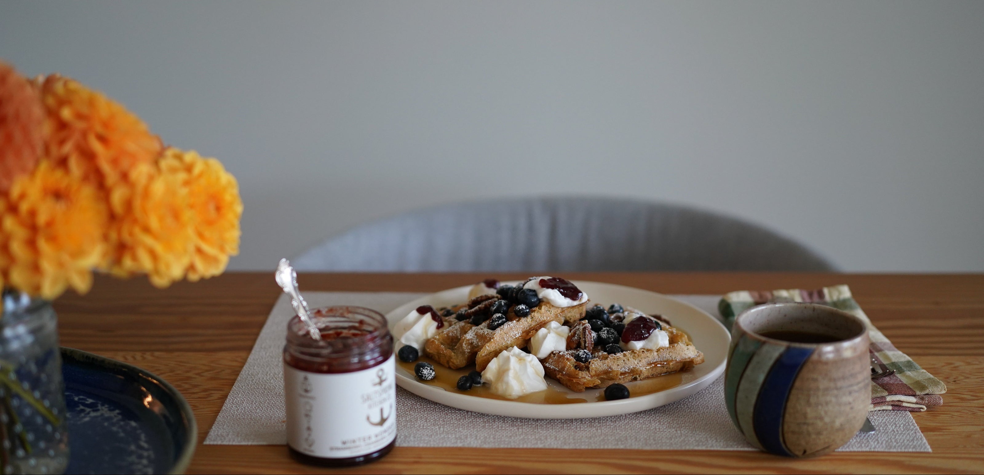 Breakfast setting with waffles, syrup, and a cup on a wooden table.